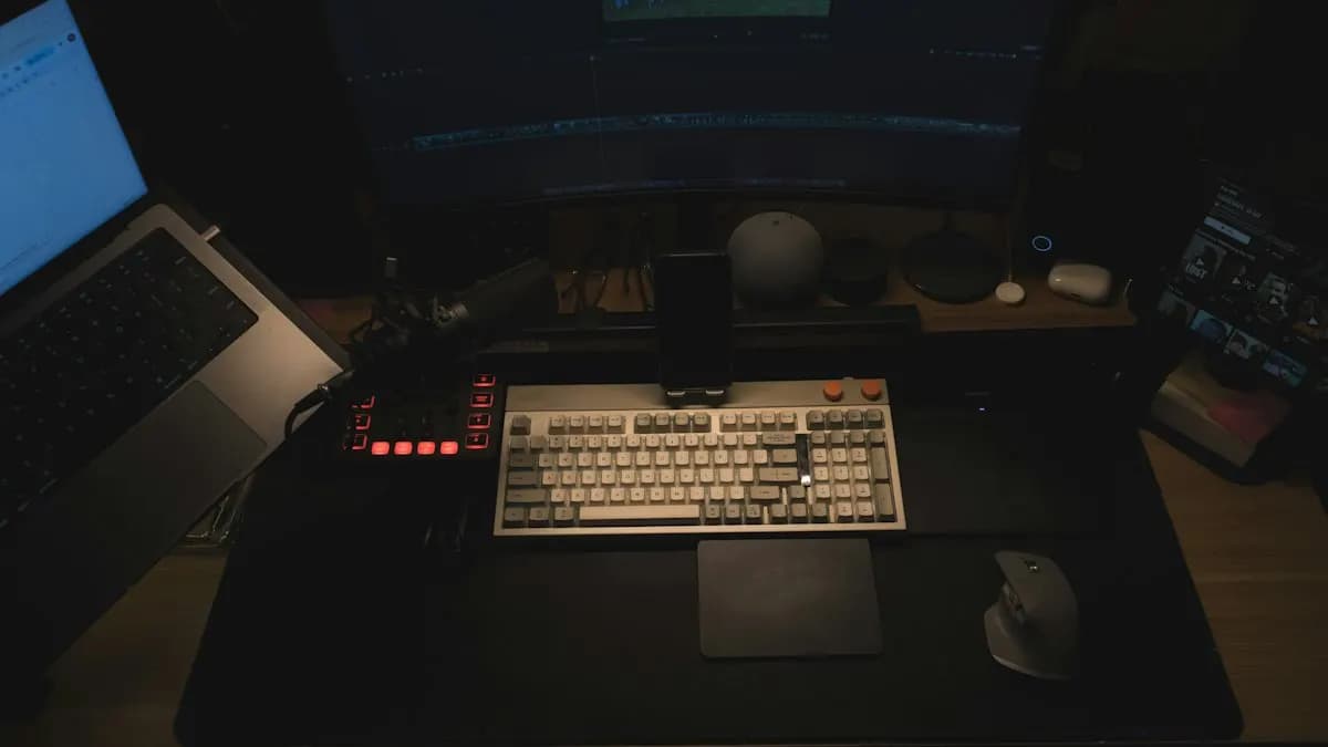 Dark animation desk with a laptop, keyboard and monitor set up for motion design work