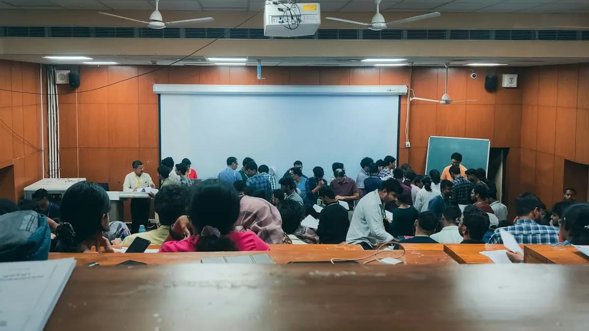 College students seated in a large classroom facing a projector screen during a lecture