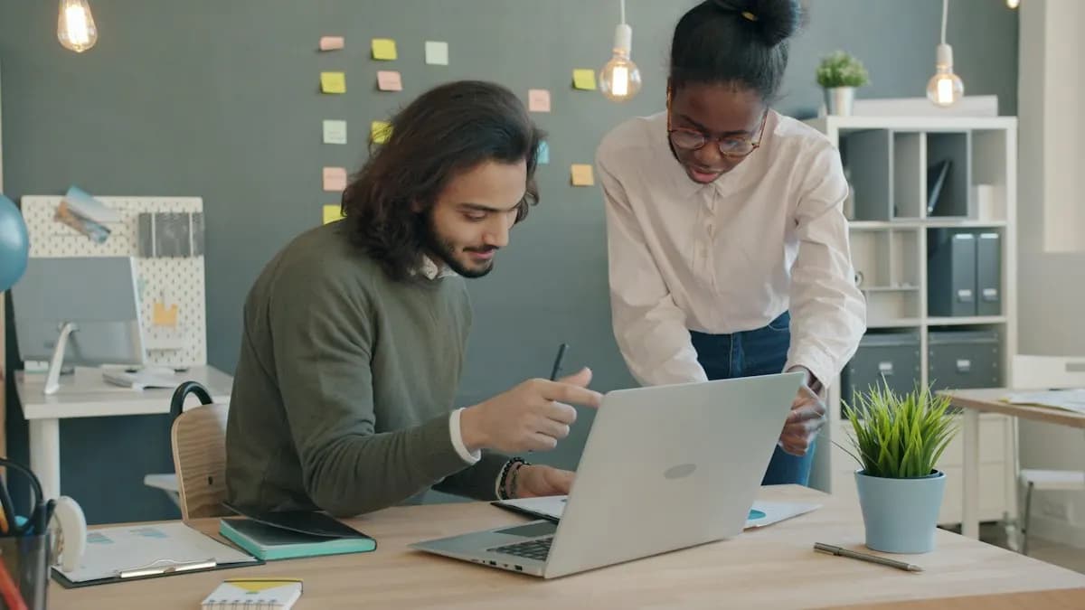 Two young marketing interns working together on a laptop in a bright office