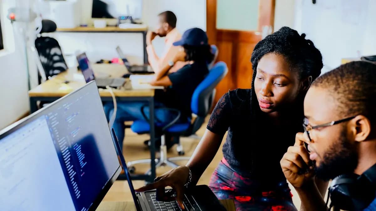 Two digital marketing students reviewing campaign work together on a laptop in a training room
