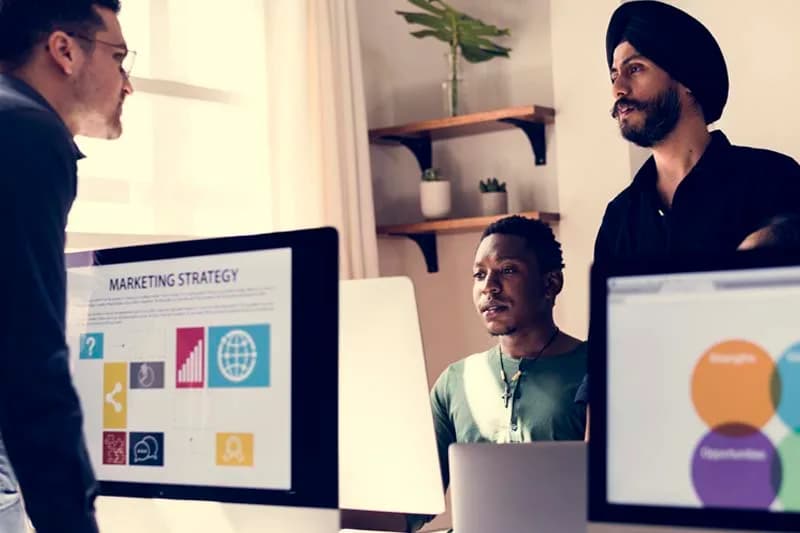 Digital marketing professional analysing campaign data on a laptop and large display