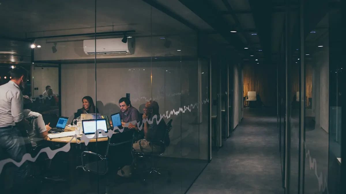 Marketing team working on laptops in a glass meeting room in the evening