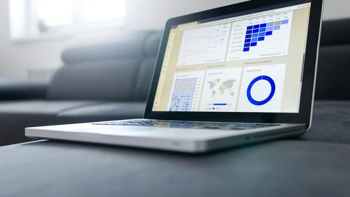 Laptop on a desk showing an analytics dashboard with charts and data tables
