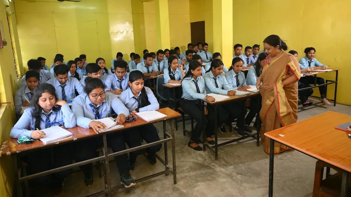 Students in school uniform at desks in a classroom while a teacher teaches