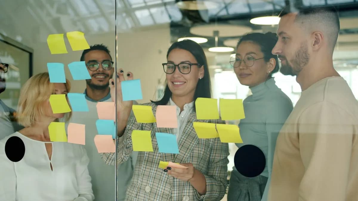 Marketing team planning a campaign with coloured sticky notes on a glass wall in an office
