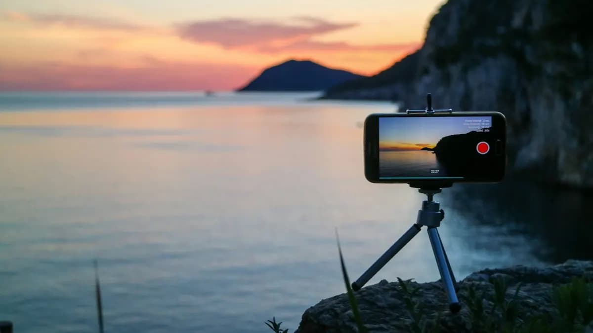 Smartphone on a small tripod filming a vertical video by the sea at sunset