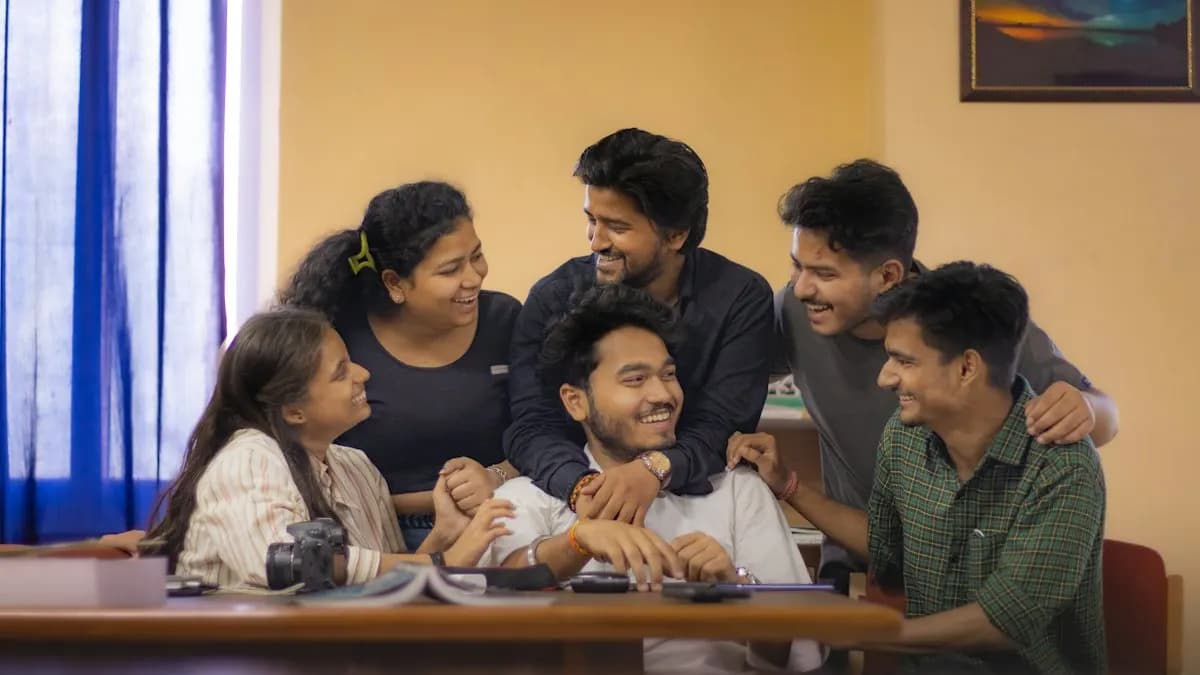 Group of Indian college students smiling together around a study table after 12th