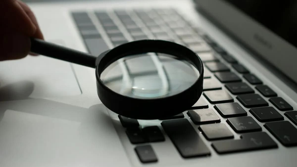 Hand holding a magnifying glass over a laptop keyboard, a picture of searching and research