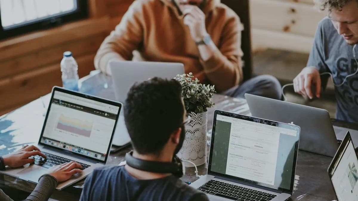 Team of young professionals working on laptops around a wooden table in an office