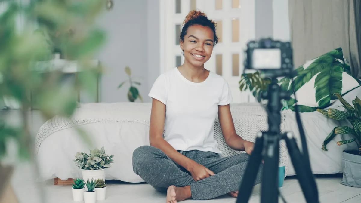 Young content creator sitting on the floor at home smiling into a camera on a tripod while recording a video