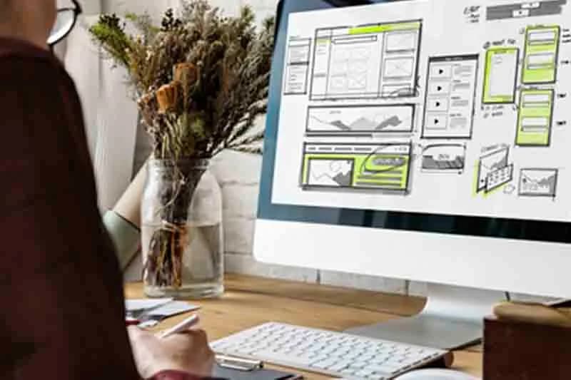 Student reviewing a web design layout on a monitor in a training lab
