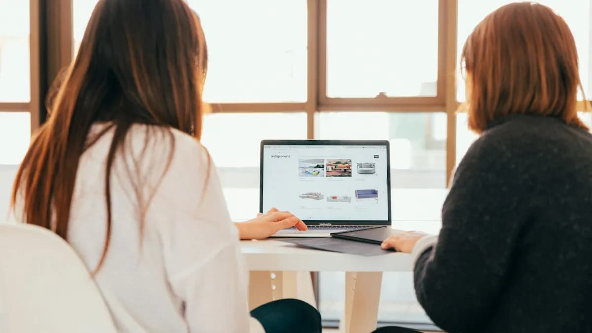 Two women at a desk looking at a laptop screen while planning keywords for a marketing campaign