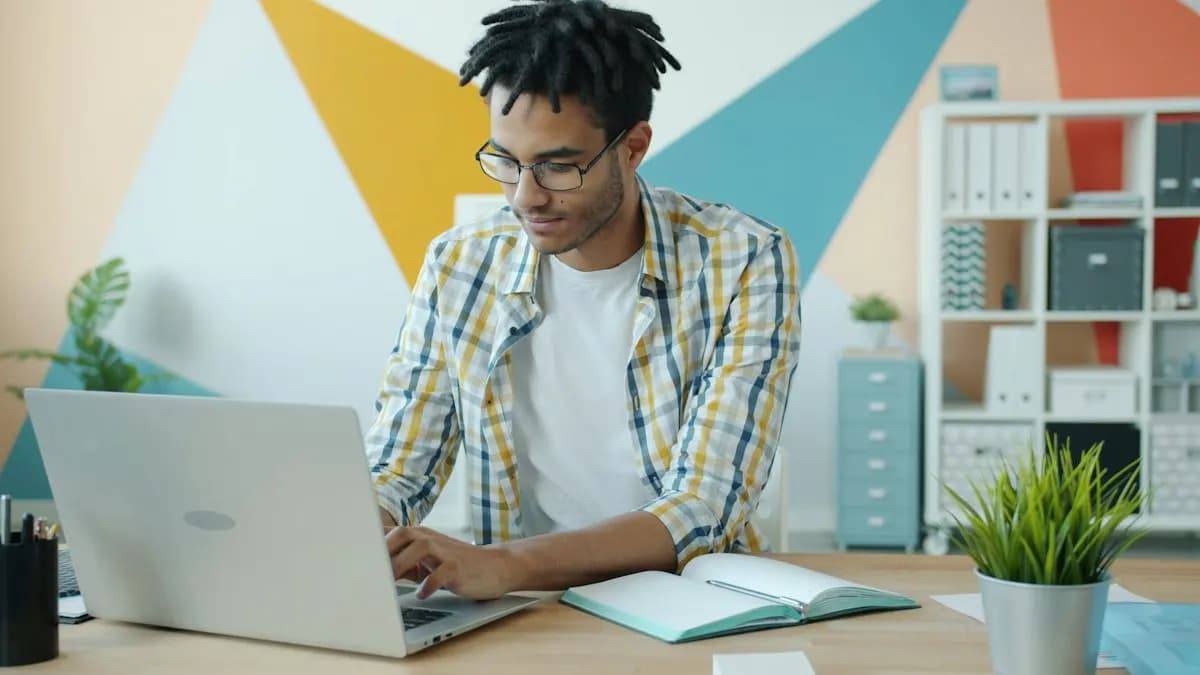 Young man in glasses typing on a laptop at a home desk during an online class