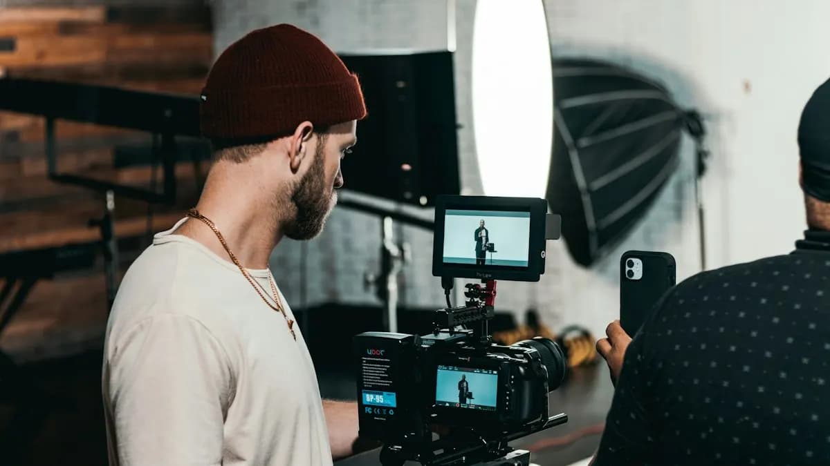 YouTube creator in a cap standing behind a video camera and monitor in a small studio