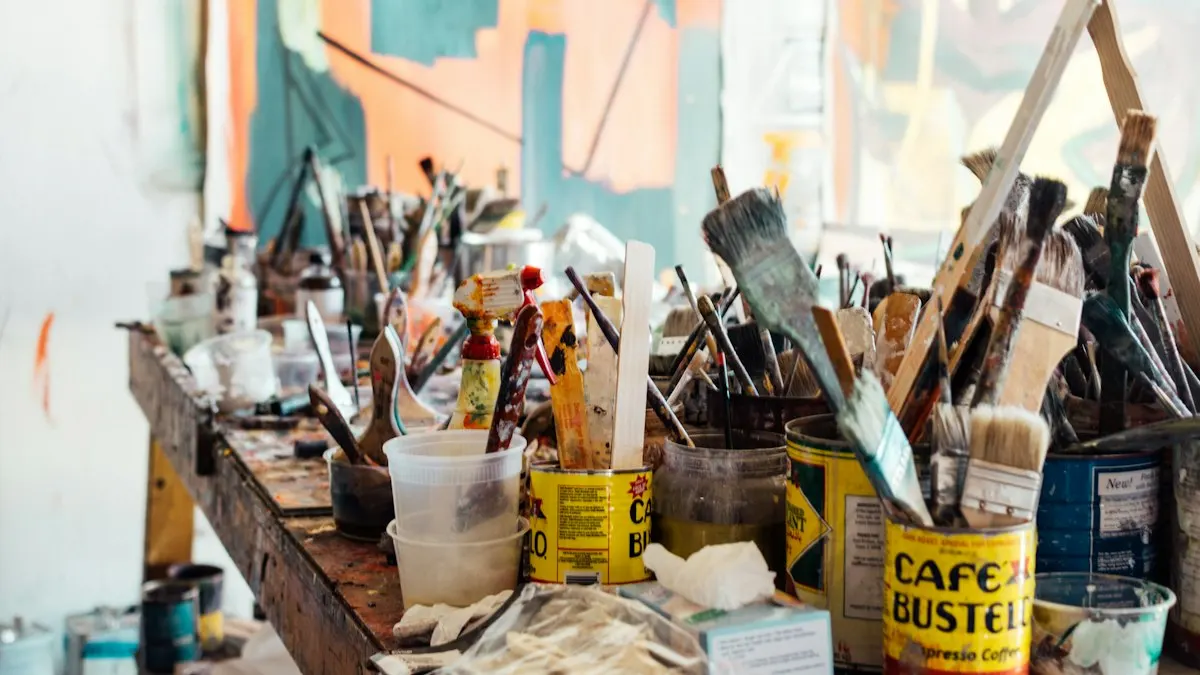 Art studio table full of paint brushes, paint tins and drawing tools used by arts students
