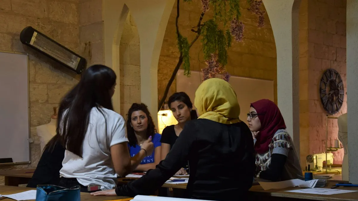 Group of design students discussing work around a table in a bright classroom
