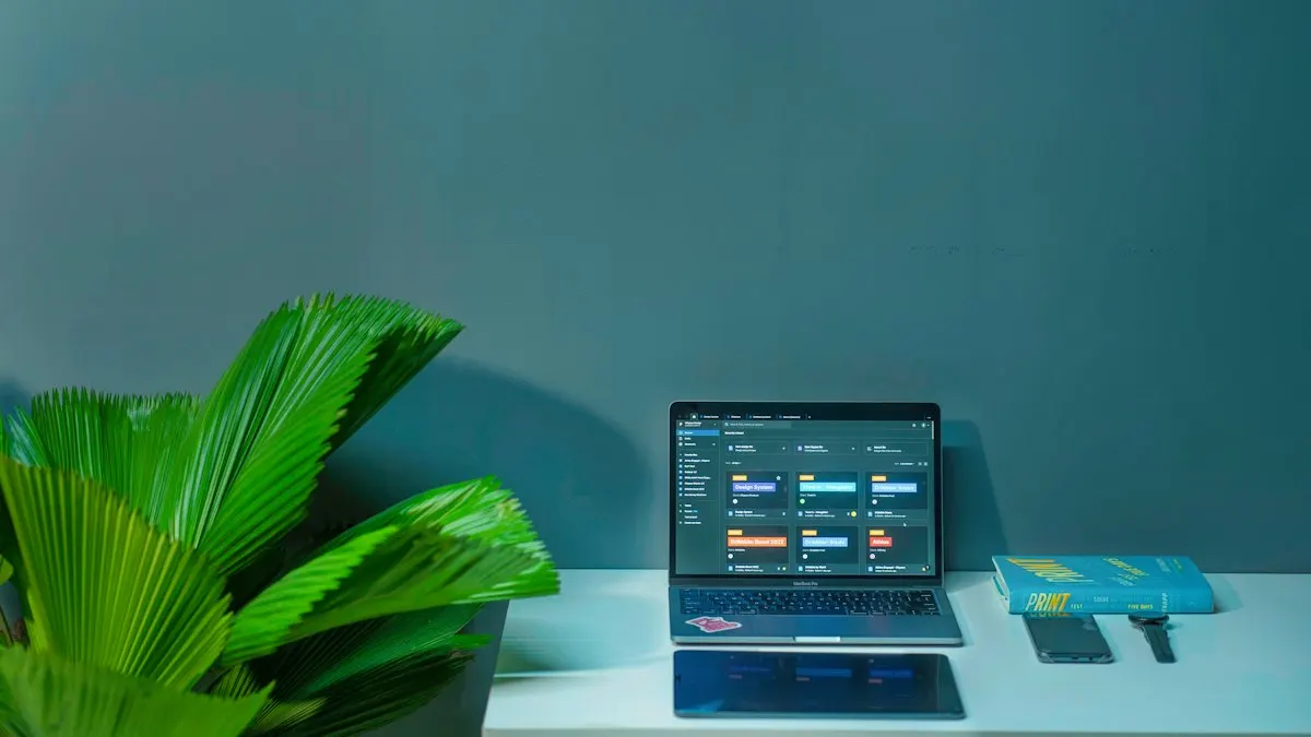 Laptop on a white desk next to a green plant showing a project board for a design portfolio
