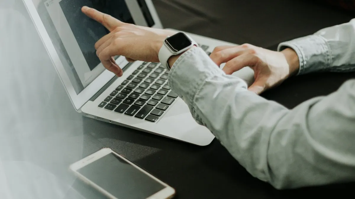 Marketer pointing at a laptop screen while reviewing campaign content with a phone on the desk