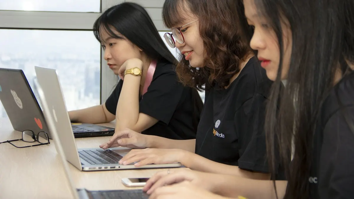 Three digital marketing students working on laptops side by side in a training session