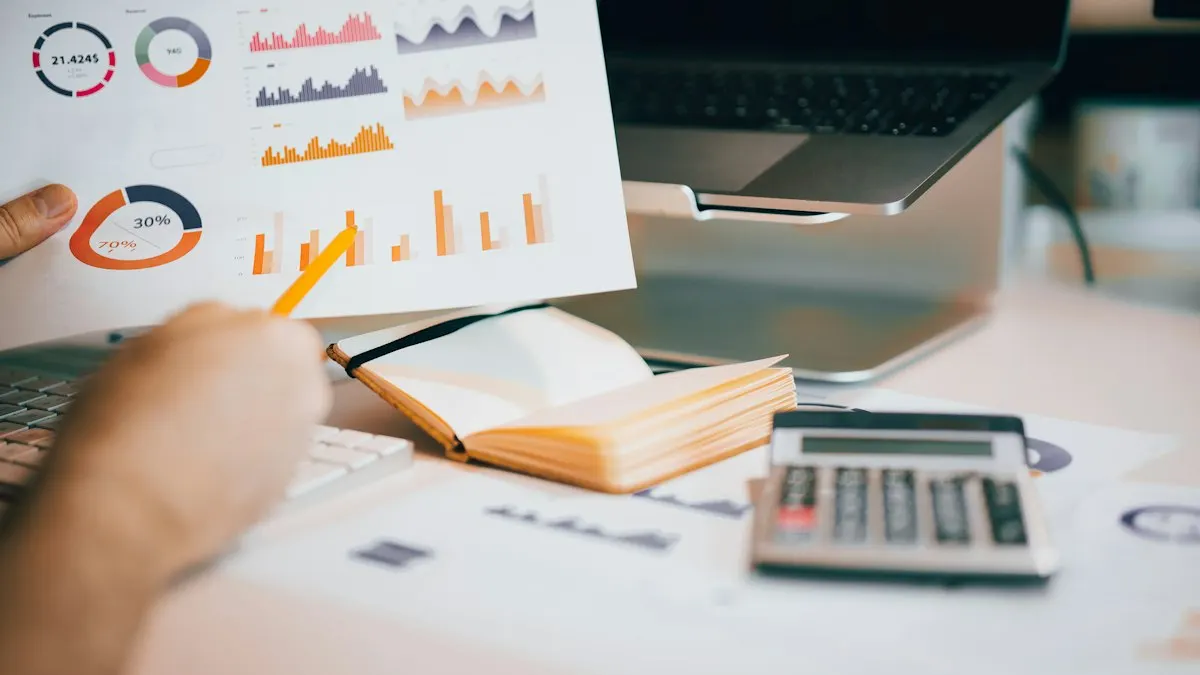 Hand pointing at marketing charts printed on paper beside a laptop and calculator