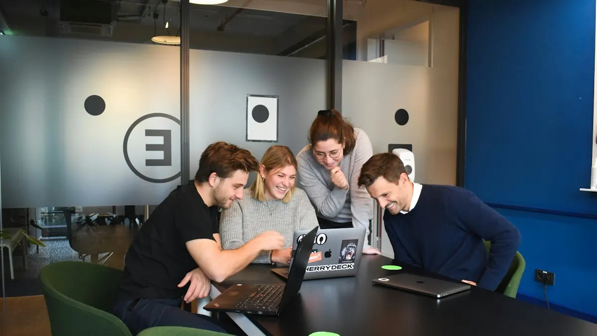 Four colleagues looking at one laptop together around a meeting table