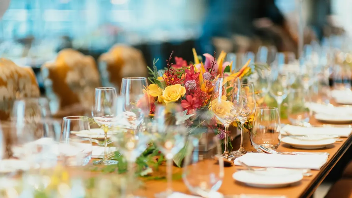 Long dinner table set with glasses and a colourful flower centrepiece at an event