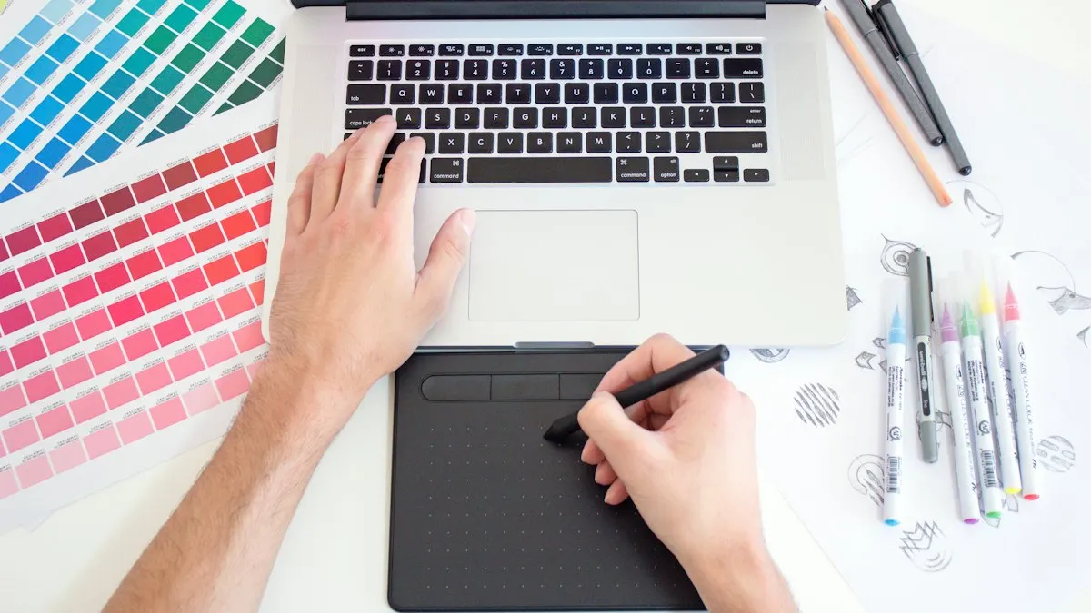 Graphic designer using a pen tablet and laptop beside colour swatches and markers