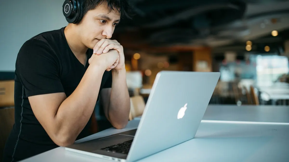 Young man with headphones studying an edit on his laptop in a quiet cafe