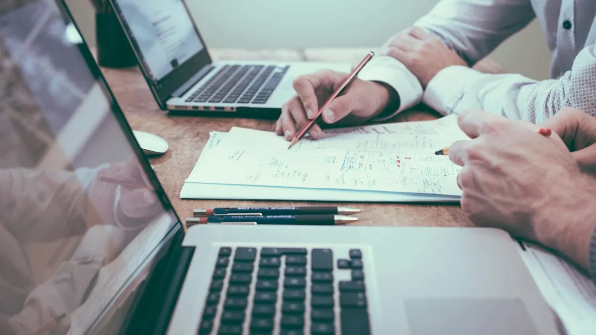Person holding a pencil beside a laptop while working through a marketing report