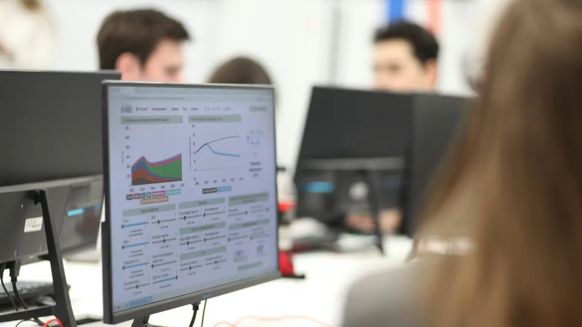 Students working at desktop computers in a busy training lab with charts on the nearest screen