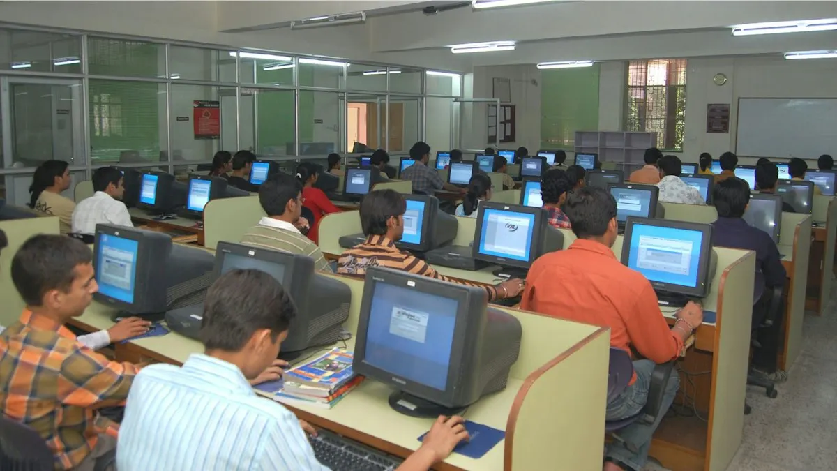 Students working at rows of computers in a busy Indian computer lab